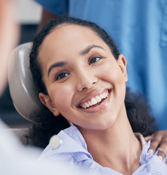 Woman in the dental chair grinning at her dentist