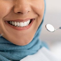 Woman smiling while dentist checks her whitening results