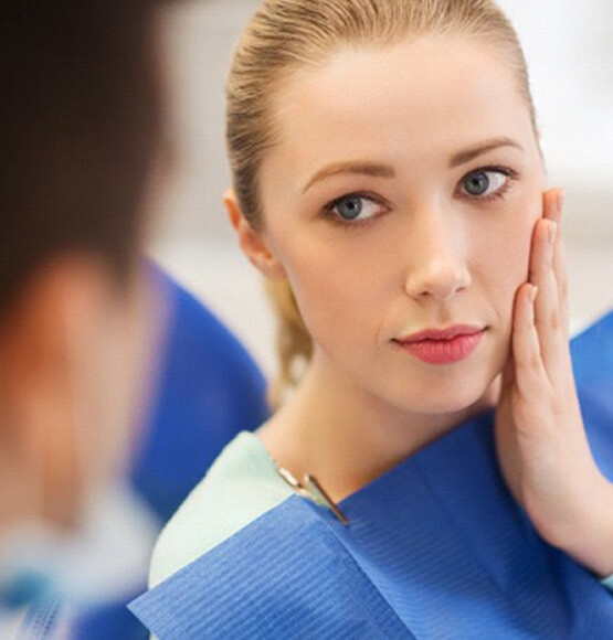 a patient holding her cheek due to tooth pain