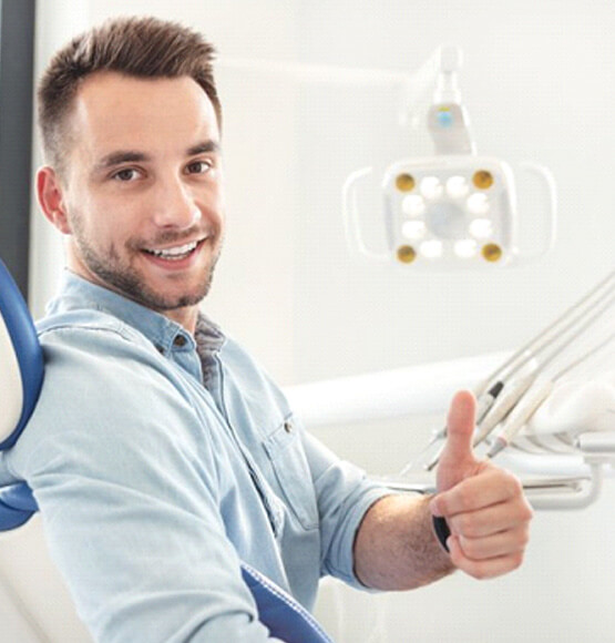 a dental patient smiling and giving a thumbs-up