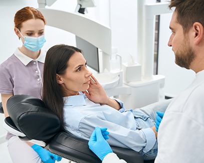 A pained woman talking to her dentist about root canal treatment