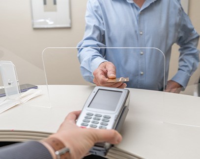 A patient using a credit card to pay for wisdom tooth extraction